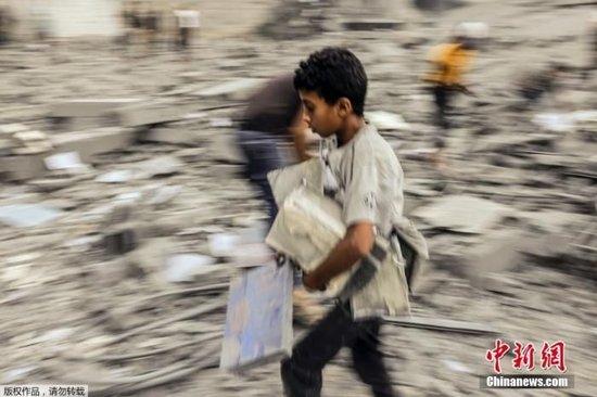 当地时间15日，沙地带南部拉法地区的废墟中，一名儿童在断壁残垣中搜寻可用的物品。