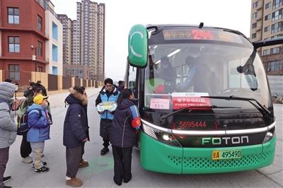 2月26日，通州区孙各庄家园小区南门前，学生们排队上通学公交车。新京报记者 王贵彬 摄