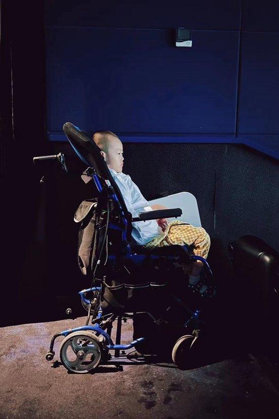 小学生邹维洛开学前看电影，第一次被工作人员允许坐在轮椅上观影。