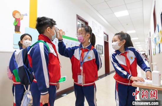 天津中小学今日恢复线下教学，图为天津市和平区万全第二小学的学生在完成第二次测温进班级 王在御 摄