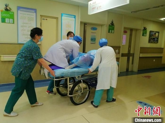 助产士刘琳琳在平车上以半跪的姿态托举住胎儿脐带。董宇翔摄