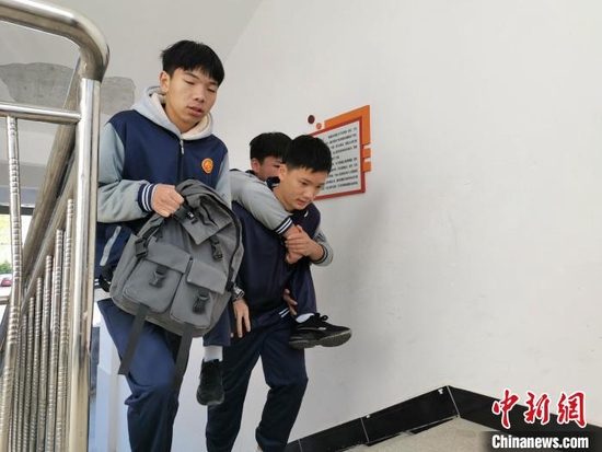 图为刘宇、袁财有一起帮助徐淮回到教室上学。刘兆春摄