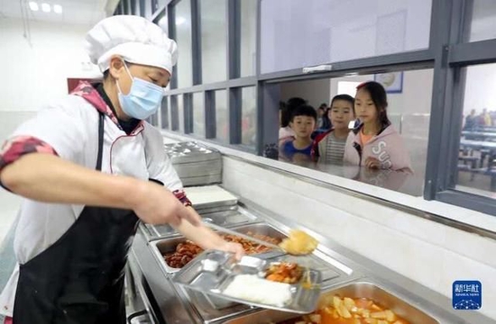 ▲资料图：四川省华蓥市高兴镇小学食堂的工作人员在给学生发放午餐。图/新华社