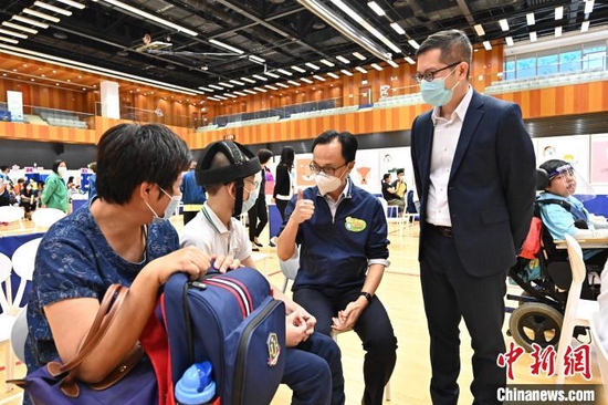 香港特区政府公务员事务局局長聂德权（右二）到儿童社区疫苗接种中心为学生打气。香港特区政府新闻处供图