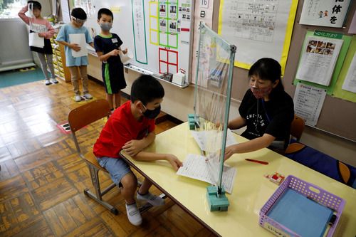 日本学校，一名教师通过塑料板与一名学生交谈。（路透社）